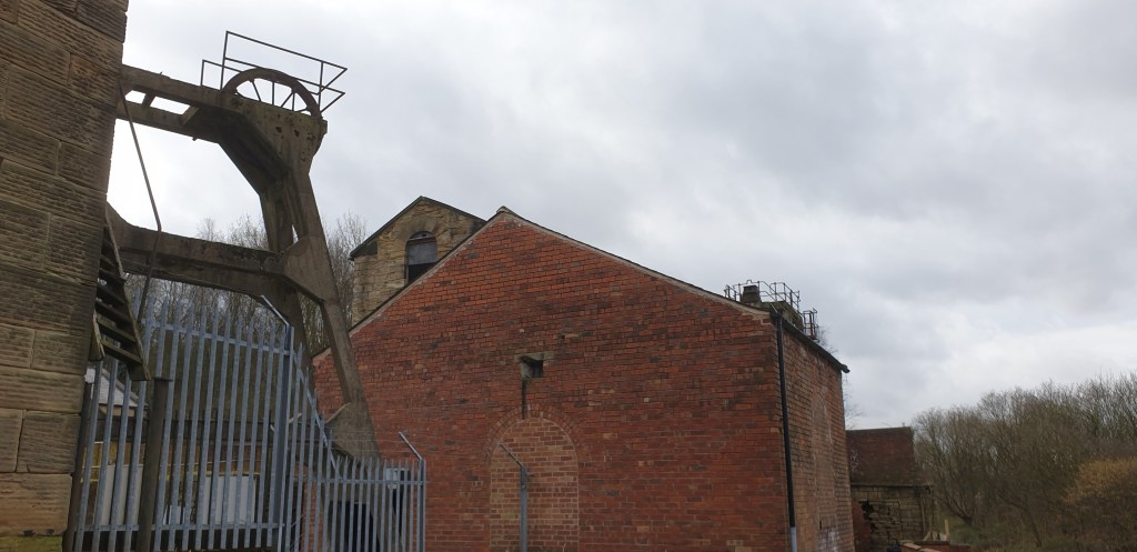 view from lower terrace of pit, pumping shaft headgear and winding engine house in view