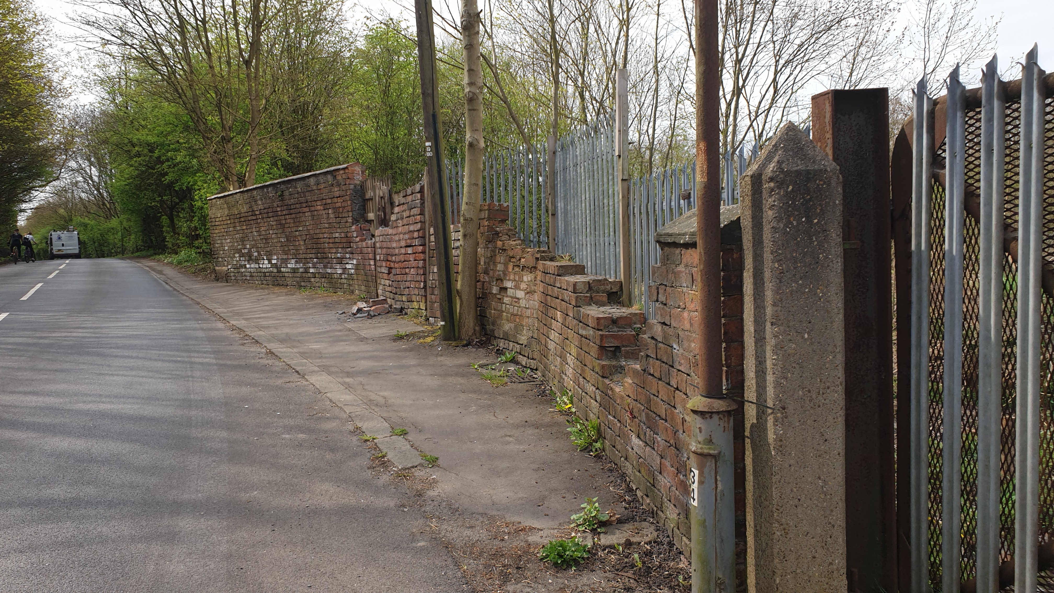 shot of the outside wall of the colliery, with some bricks on the pavement due to criminal damage