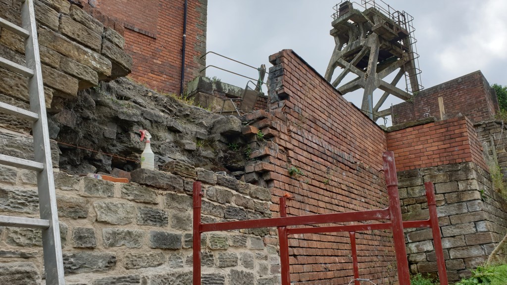 View of the repairs to the retaining wall showing a string love, new stone blocks and lime mortar
